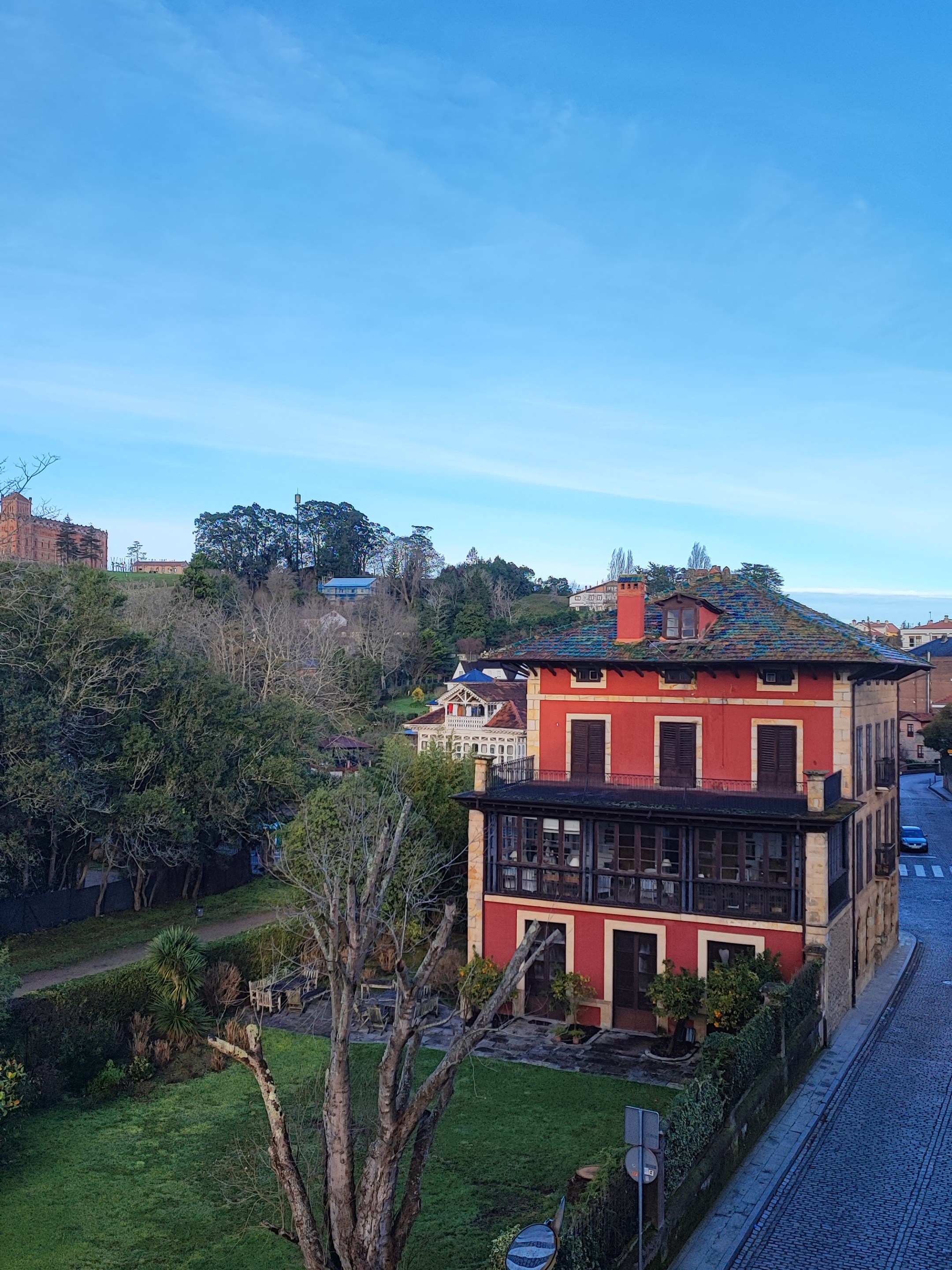 Two-story red house with a green yard and clear blue sky.