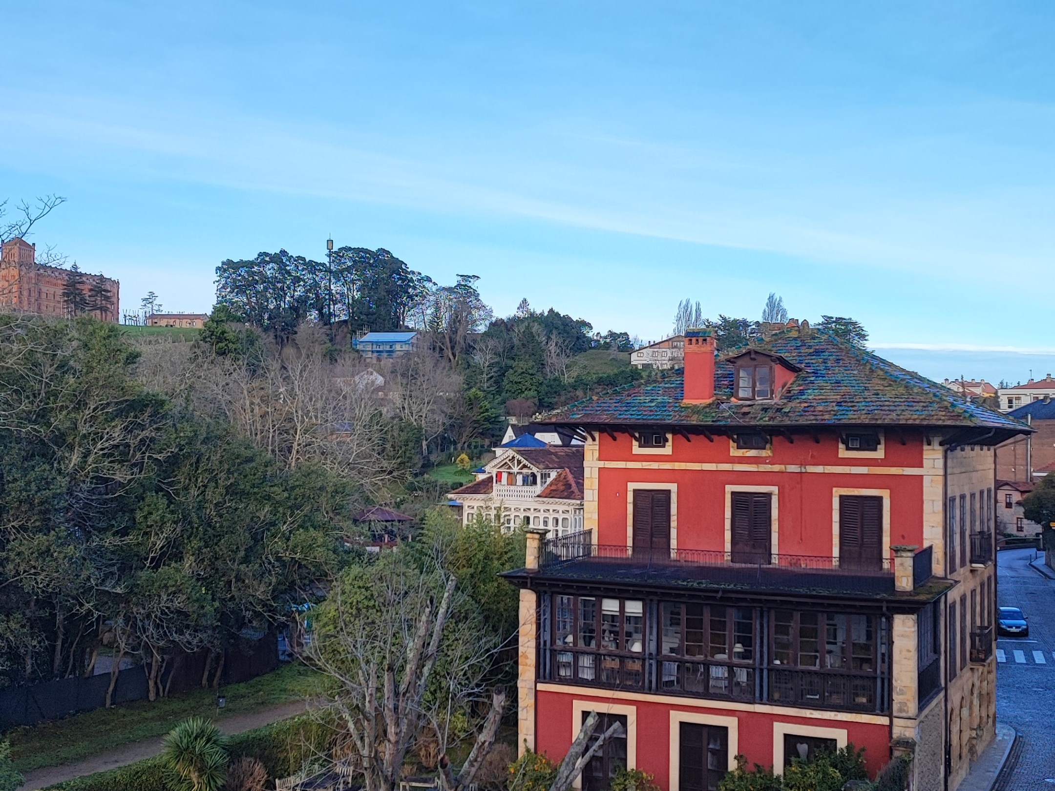 Two-story red house with a green yard and clear blue sky.