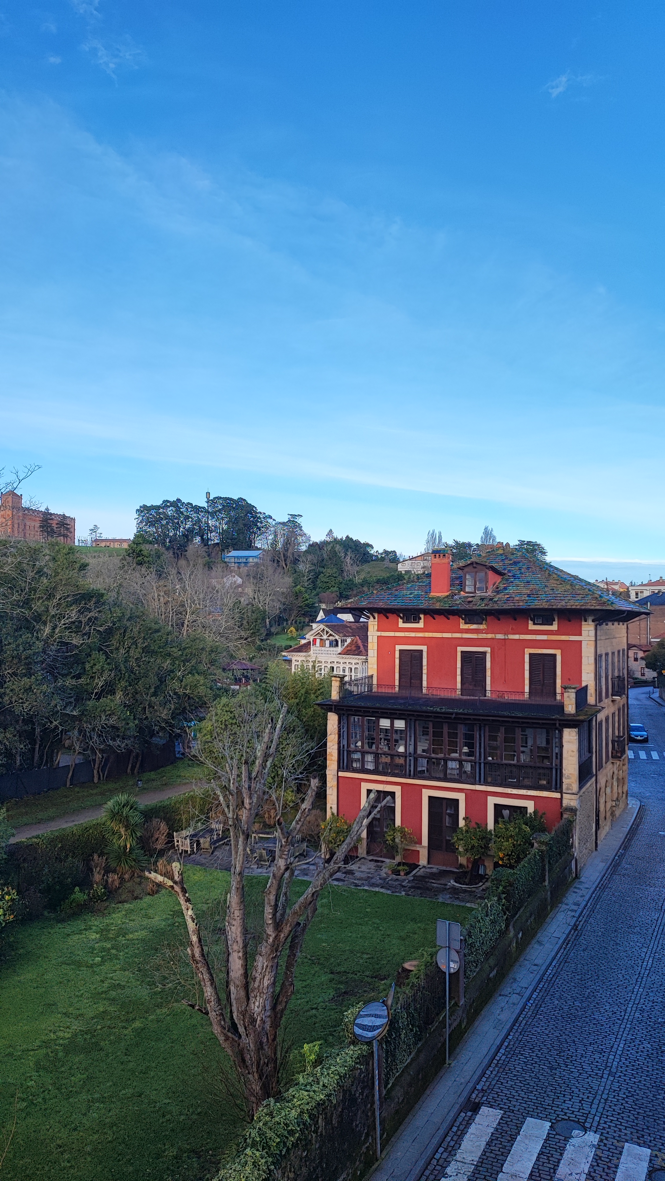 Two-story red house with a green yard and clear blue sky.