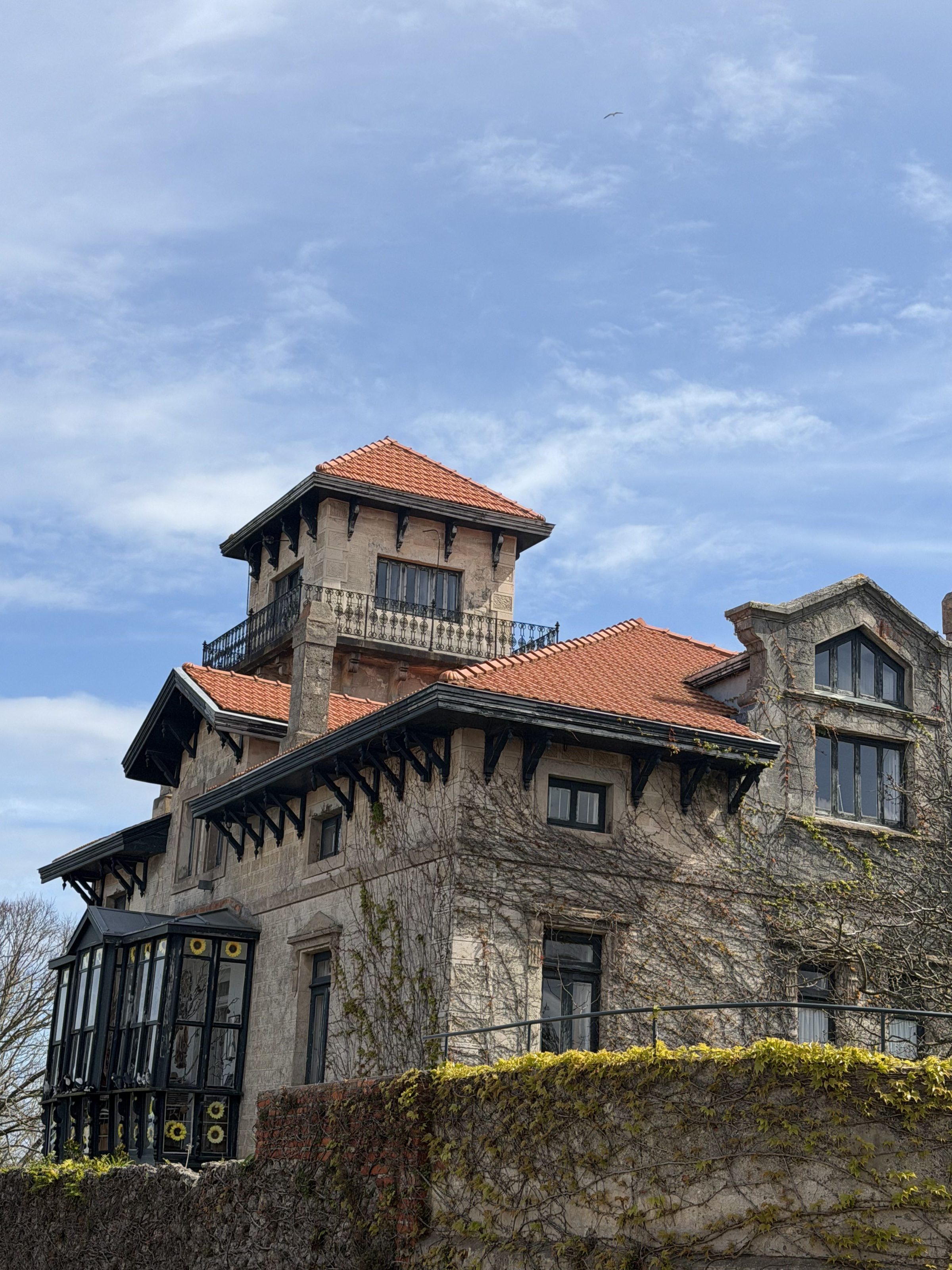 Historic building with red roof and decorative windows against blue sky.