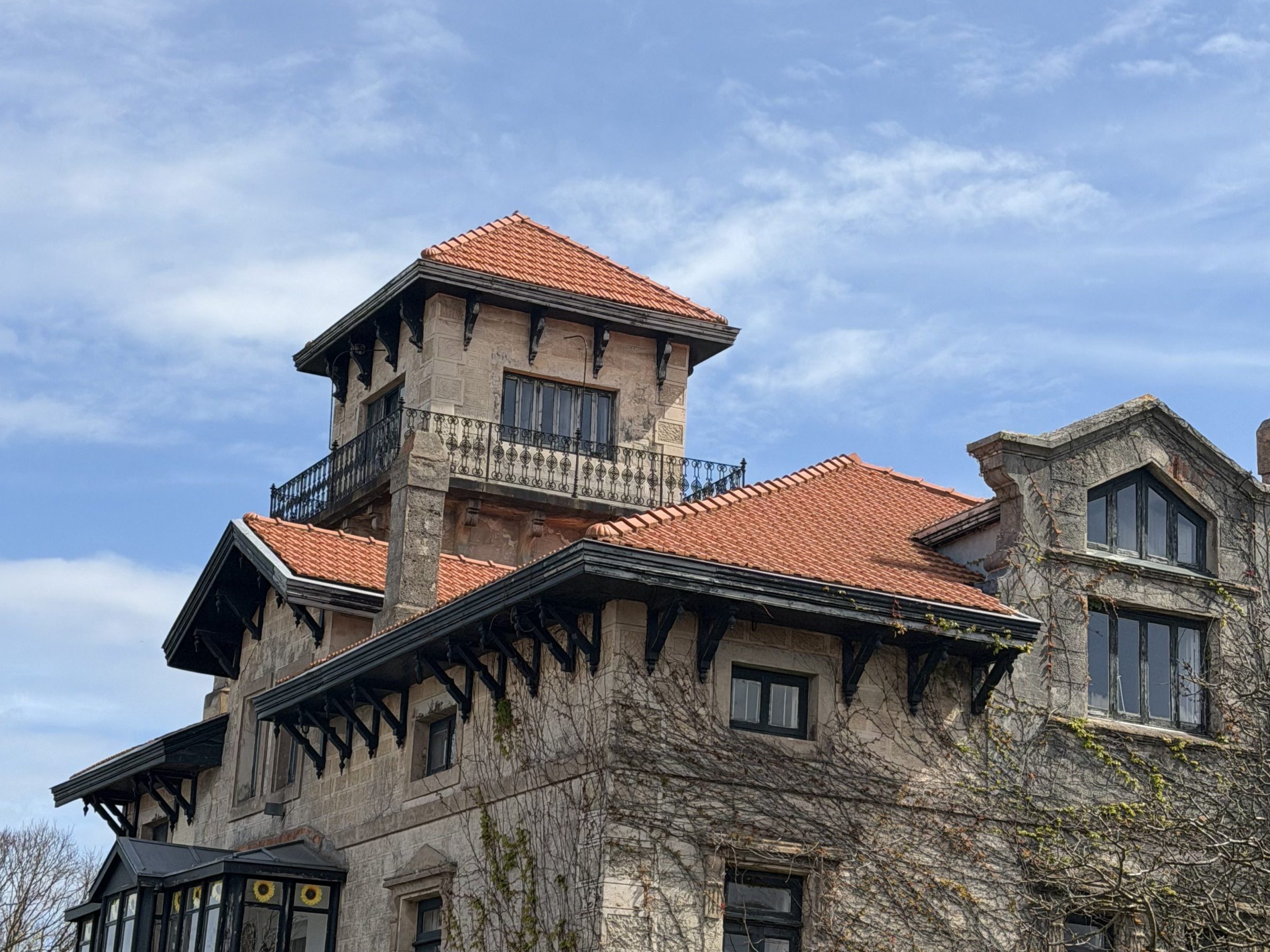 Historic building with red roof and decorative windows against blue sky.