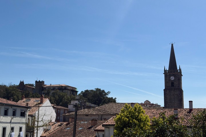 Village scene with rooftops and a clock tower under clear blue sky.