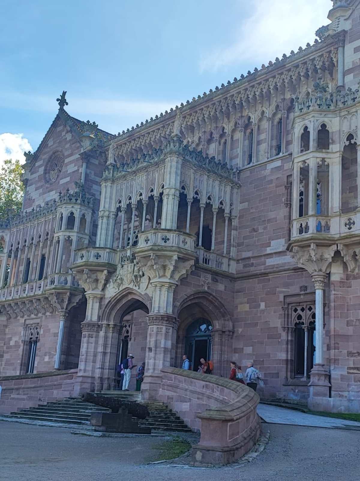 Gothic-style building with ornate facade and spire, people walking outside.