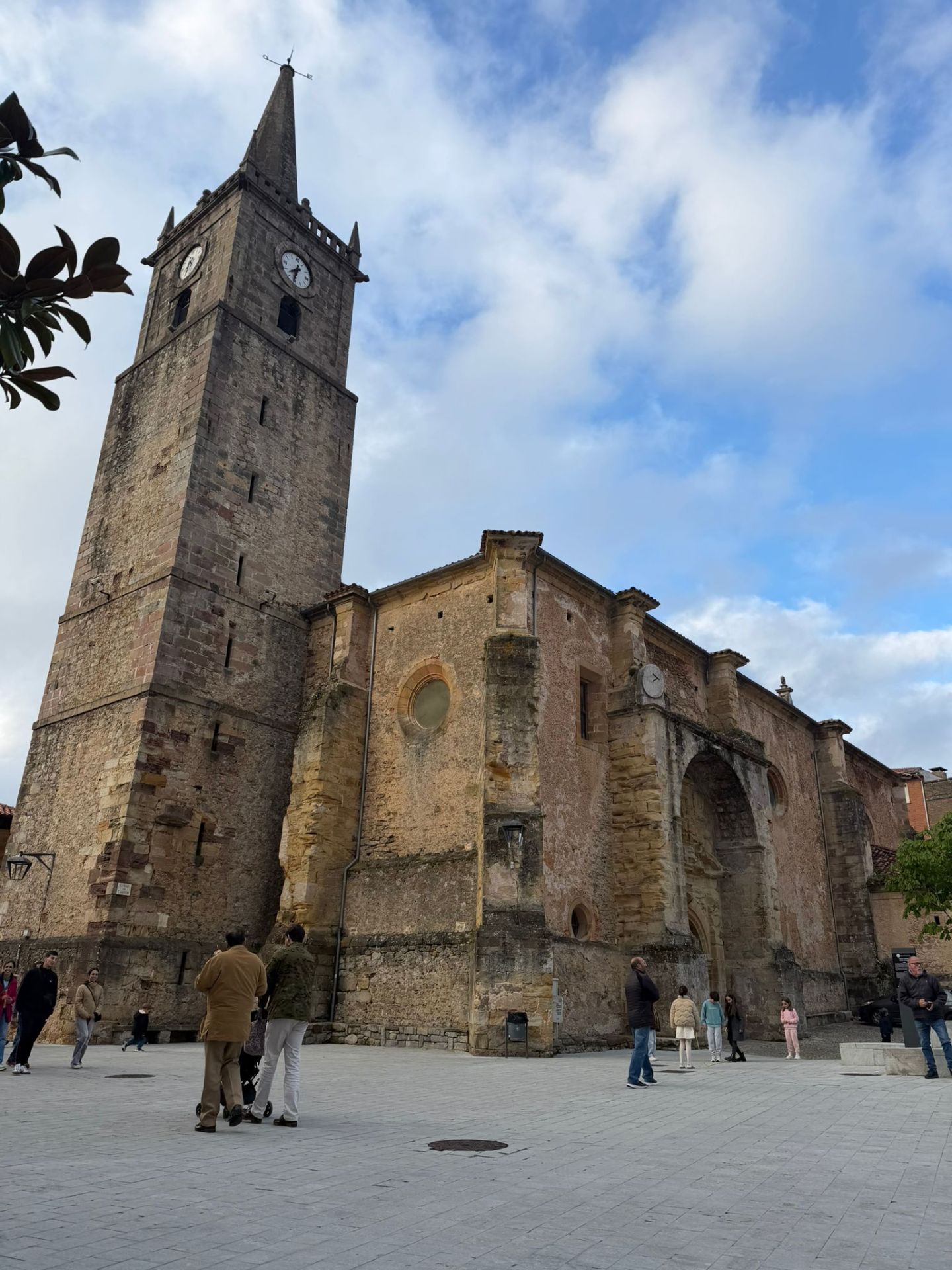 Historic stone church with tall clock tower under a cloudy sky.