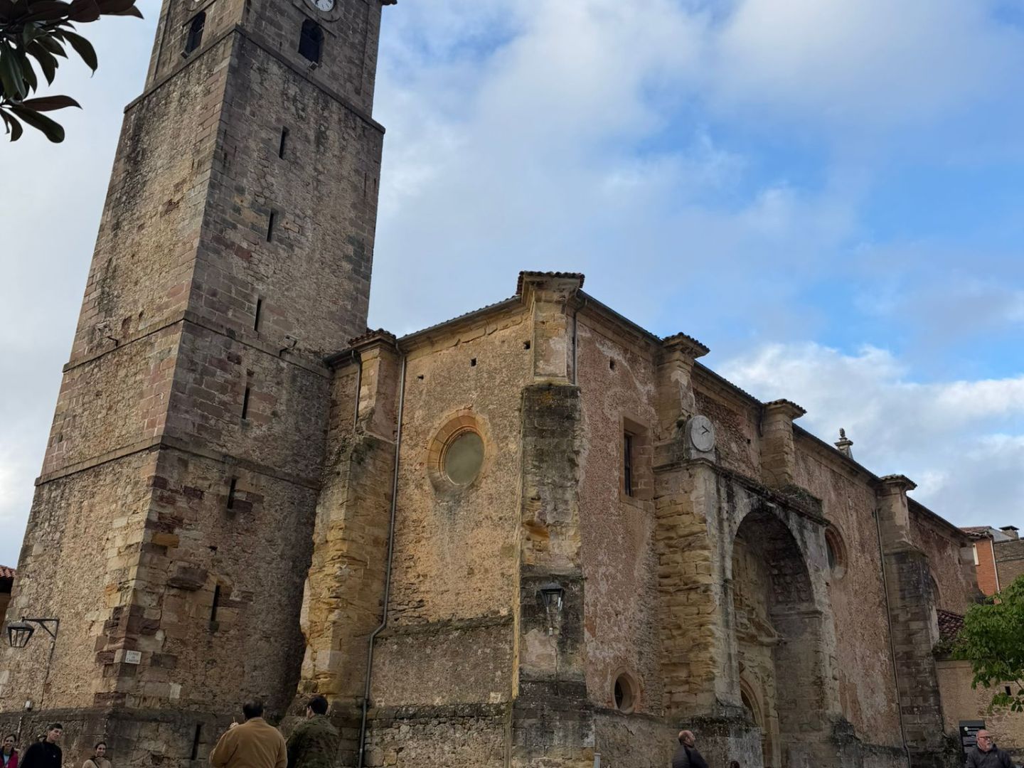 Historic stone church with tall clock tower under a cloudy sky.