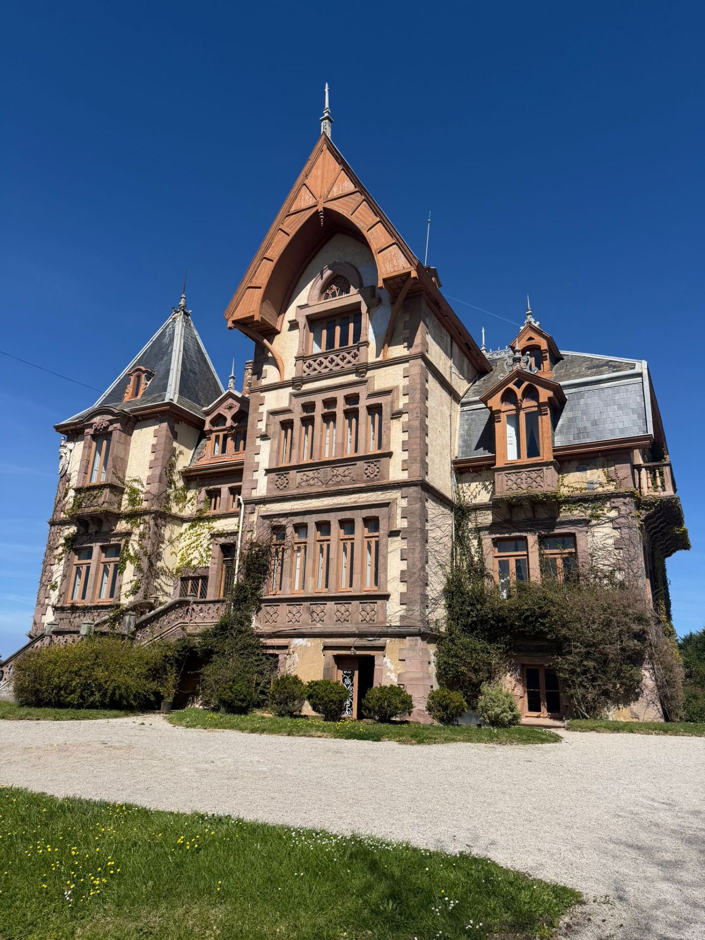 Historic mansion with turrets and arched windows against a clear blue sky.