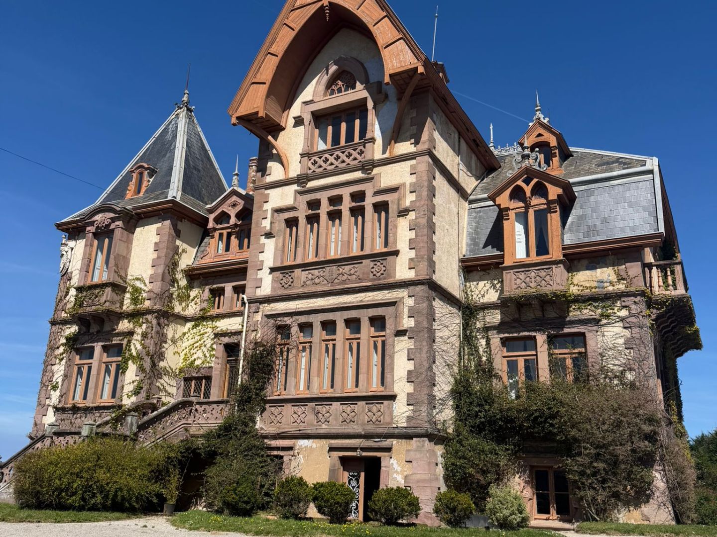 Historic mansion with turrets and arched windows against a clear blue sky.