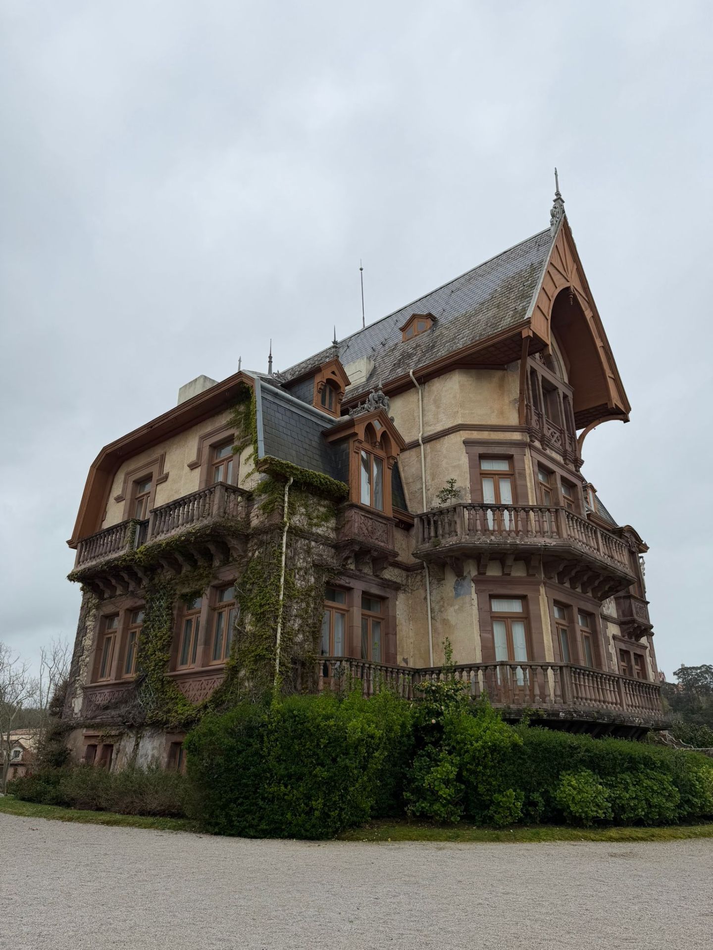 Historic multi-story house with steep roof and ivy-covered walls.