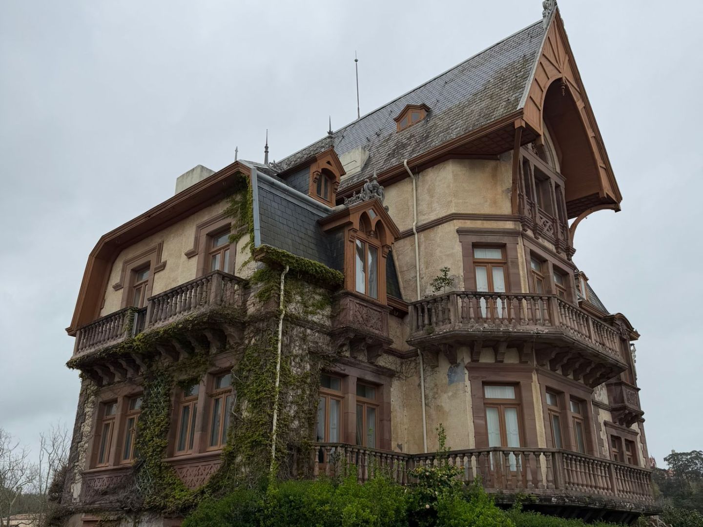 Historic multi-story house with steep roof and ivy-covered walls.