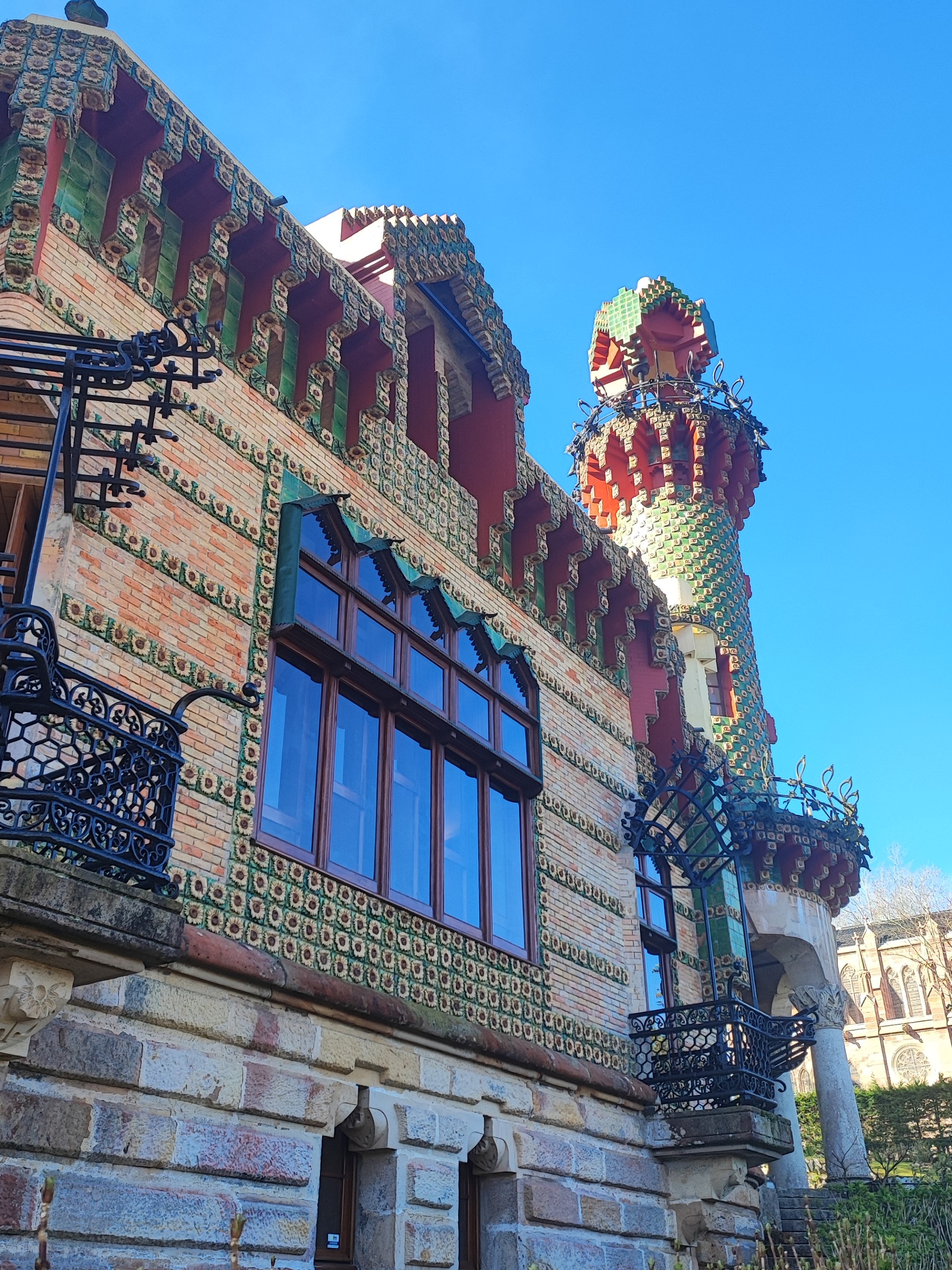 Colorful, whimsical building with tower and ornate designs, blue sky background.