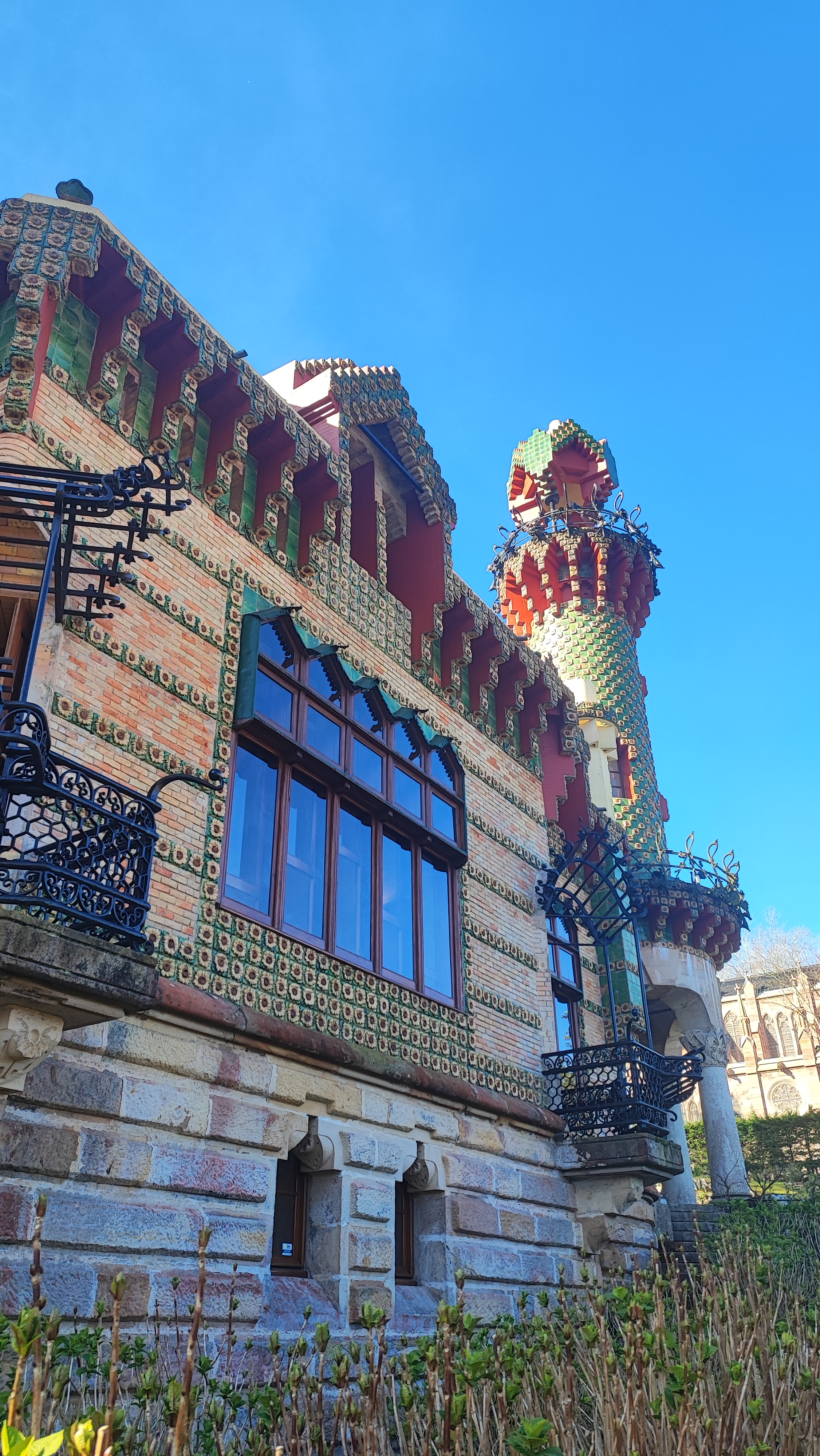 Colorful, whimsical building with tower and ornate designs, blue sky background.