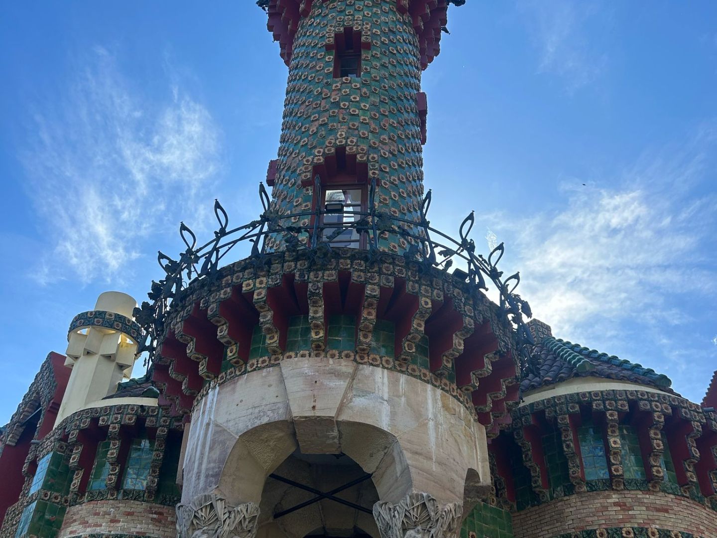Colorful eclectic tower with mosaic patterns against a blue sky.
