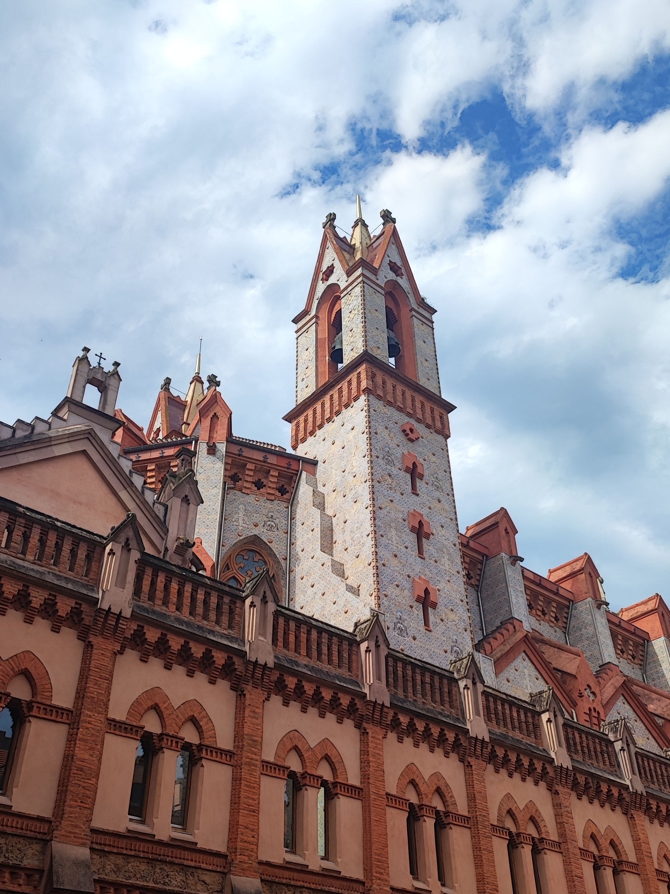 Gothic-style building with tall spires against a cloudy sky.