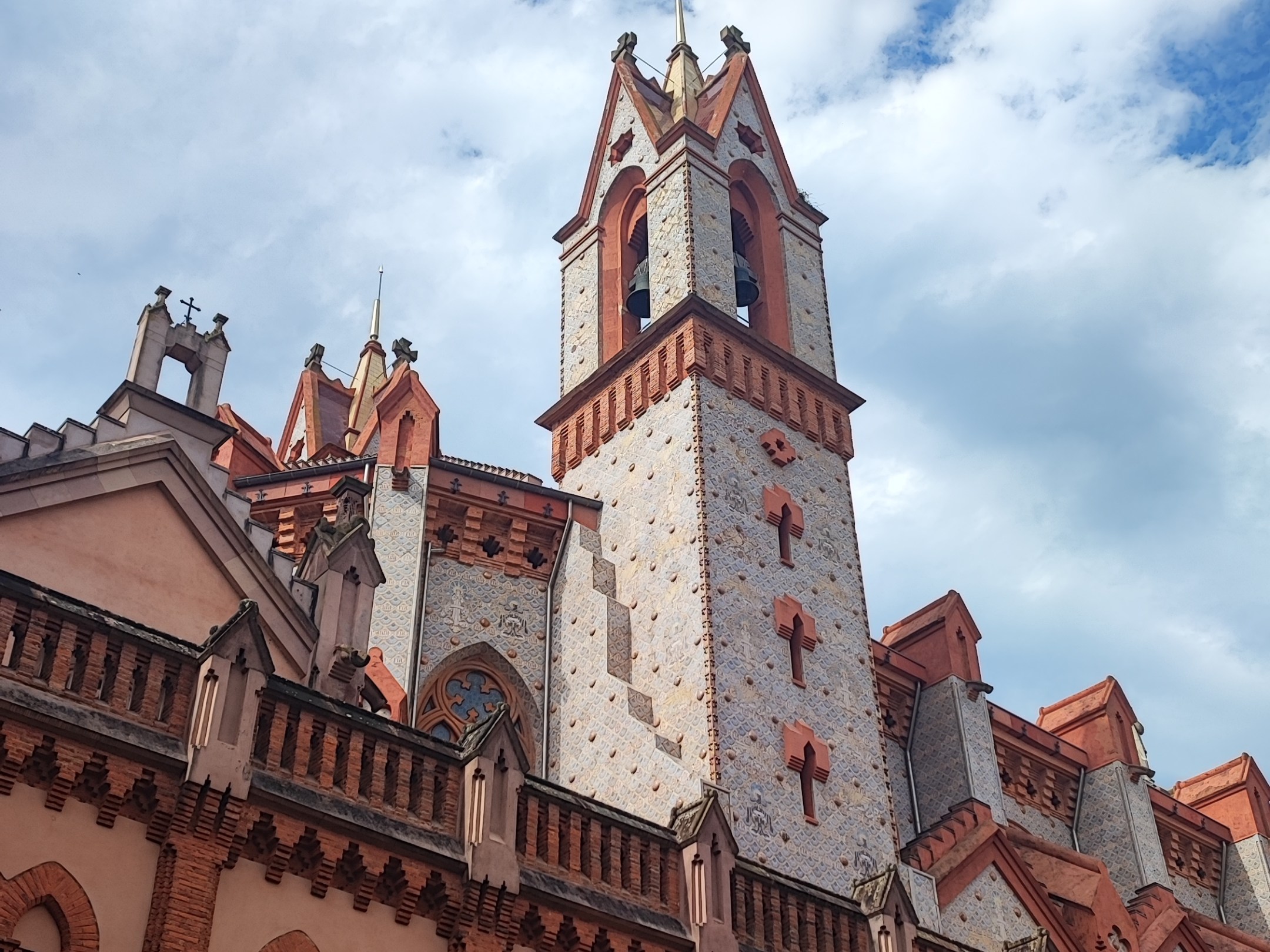 Gothic-style building with tall spires against a cloudy sky.