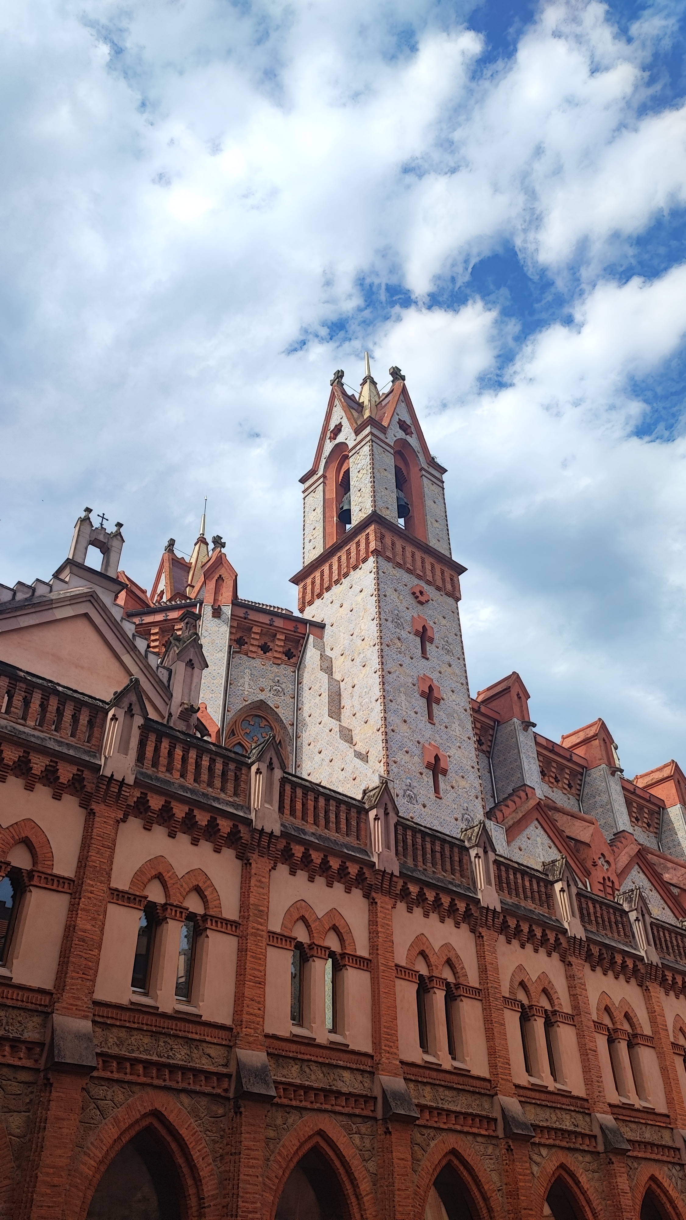 Gothic-style building with tall spires against a cloudy sky.