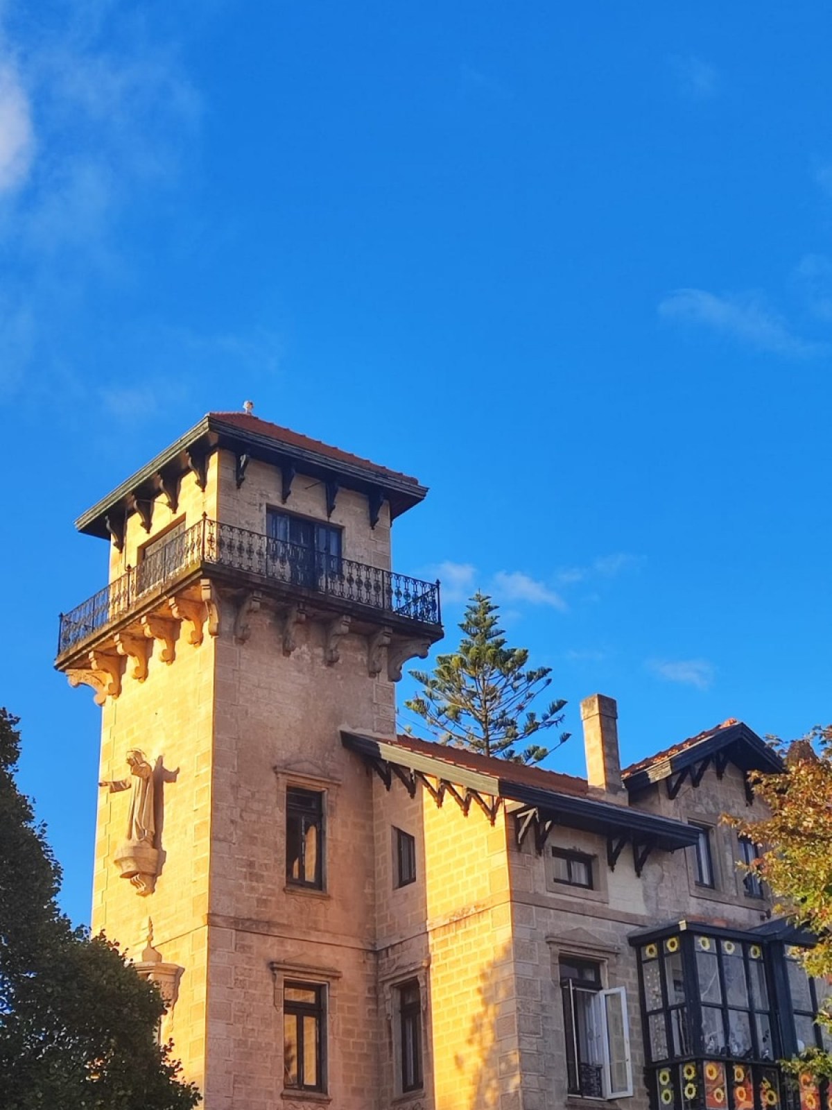 Historic building with a tall tower and ornate balcony under a clear blue sky.