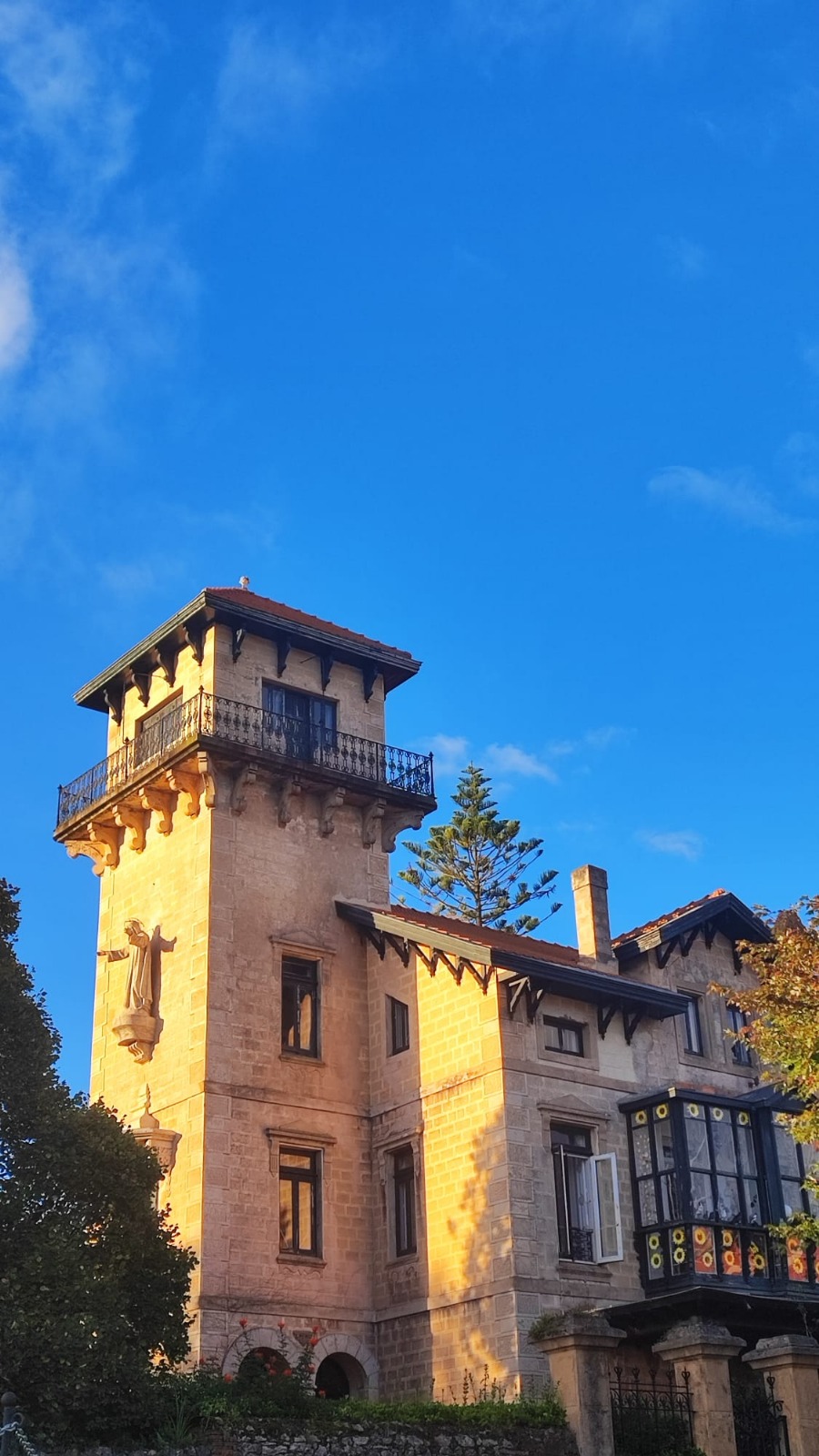 Historic building with a tall tower and ornate balcony under a clear blue sky.