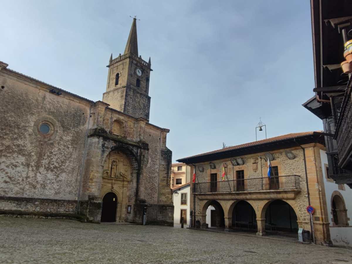 Historic church and building with arches in a cobblestone plaza.