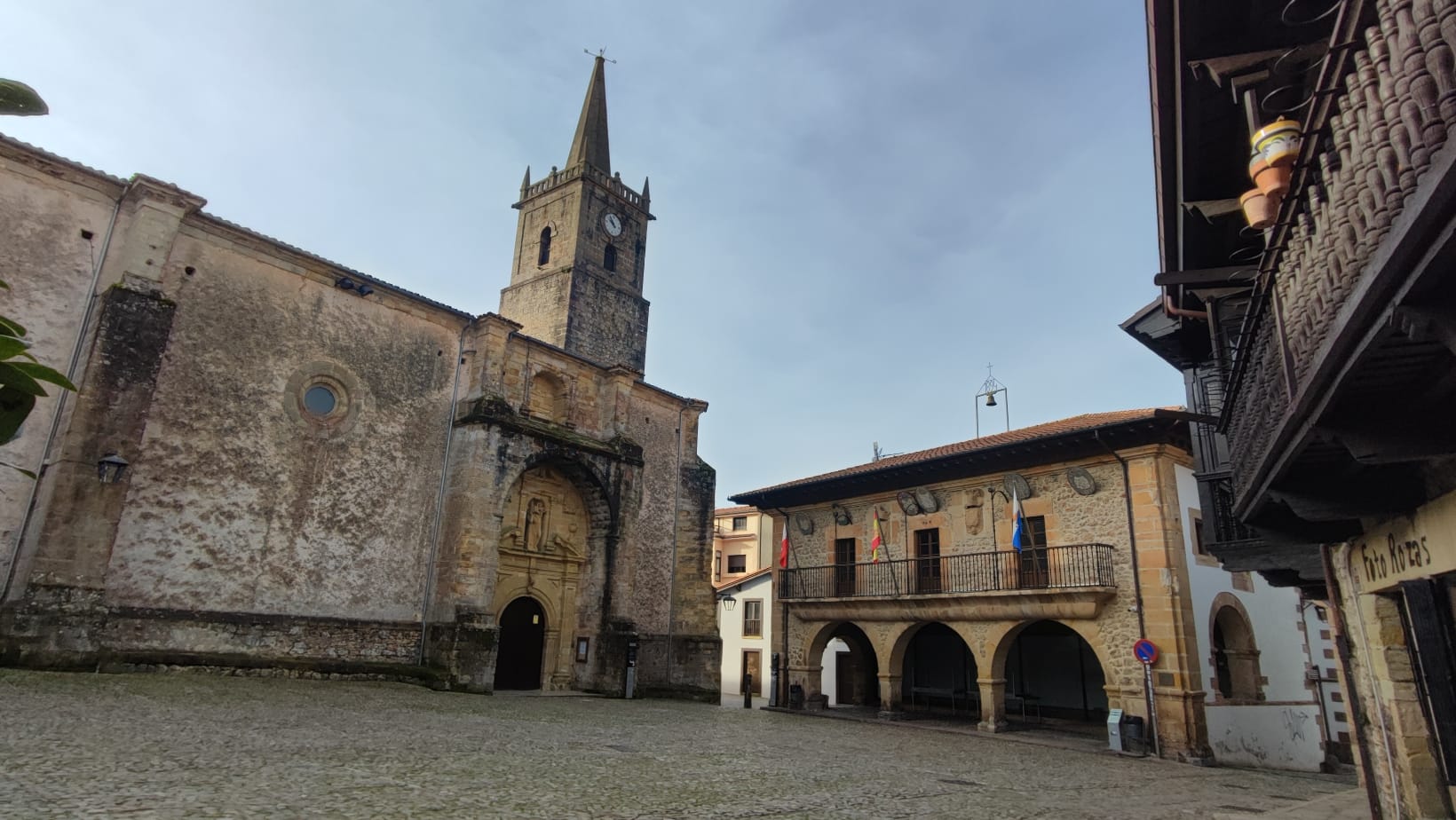 Historic church and building with arches in a cobblestone plaza.