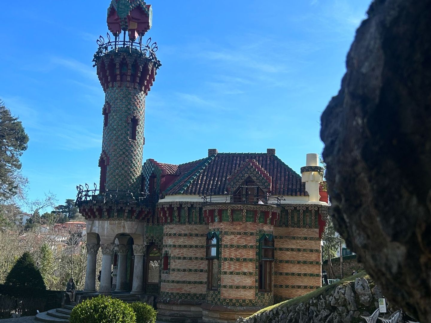 Whimsical castle with mosaic tower against clear blue sky.
