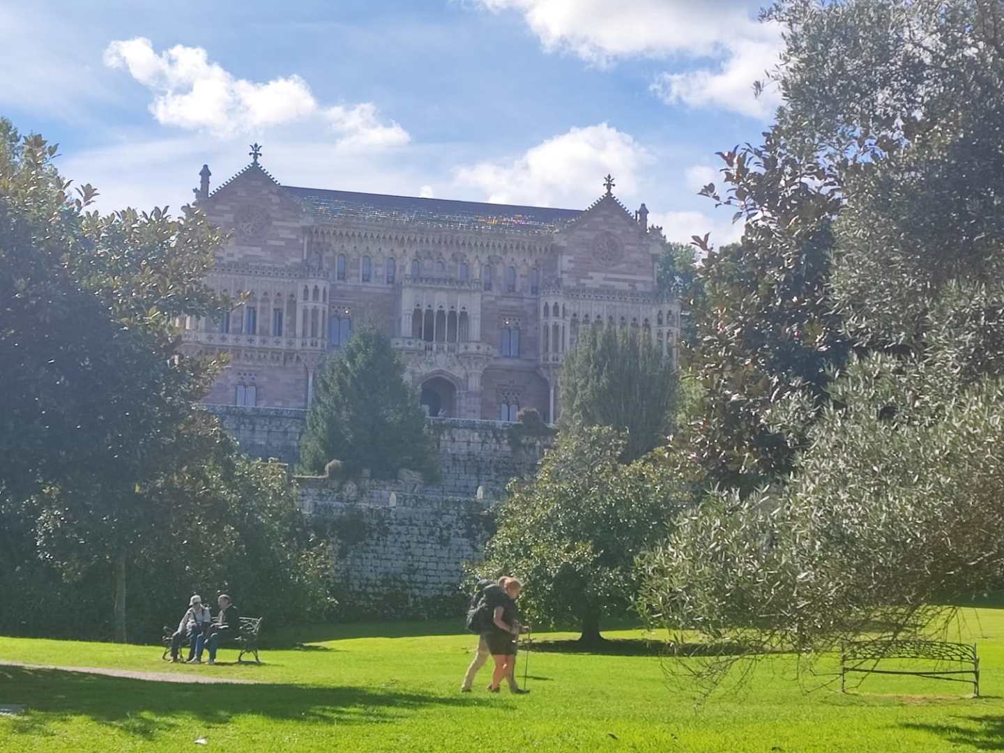 People walking in a park with a historic building in the background.