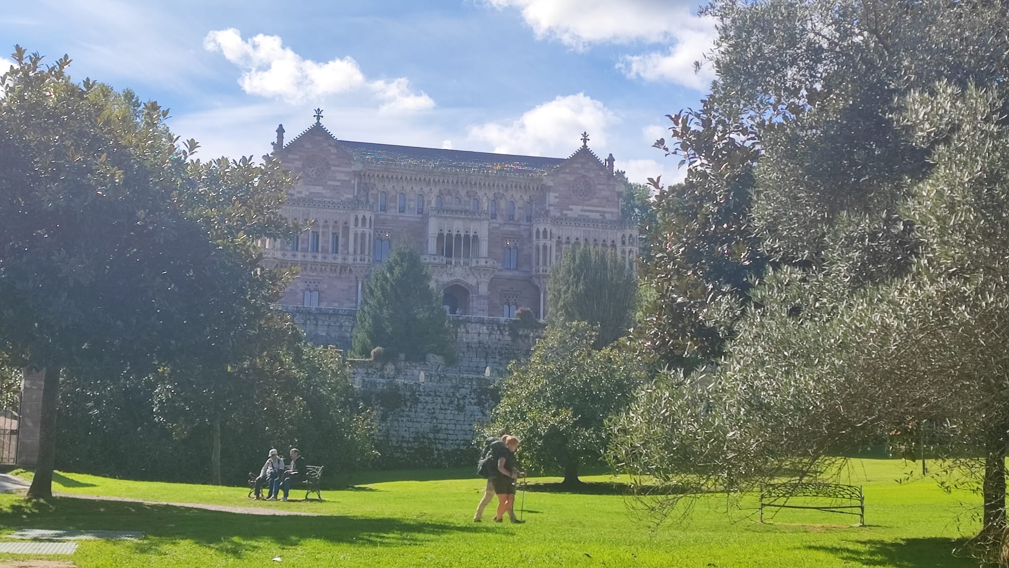 People walking in a park with a historic building in the background.