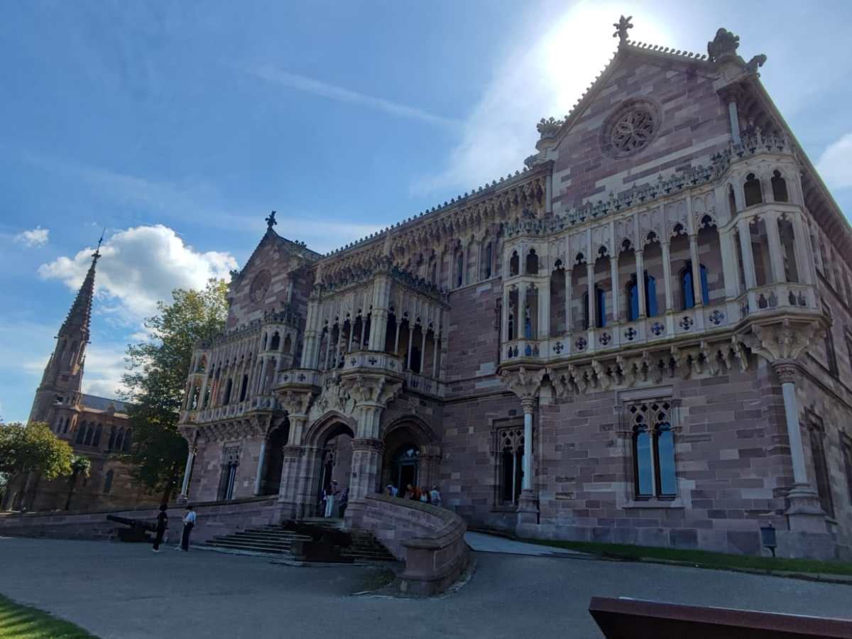 Historic castle-like building with ornate stonework under a blue sky.