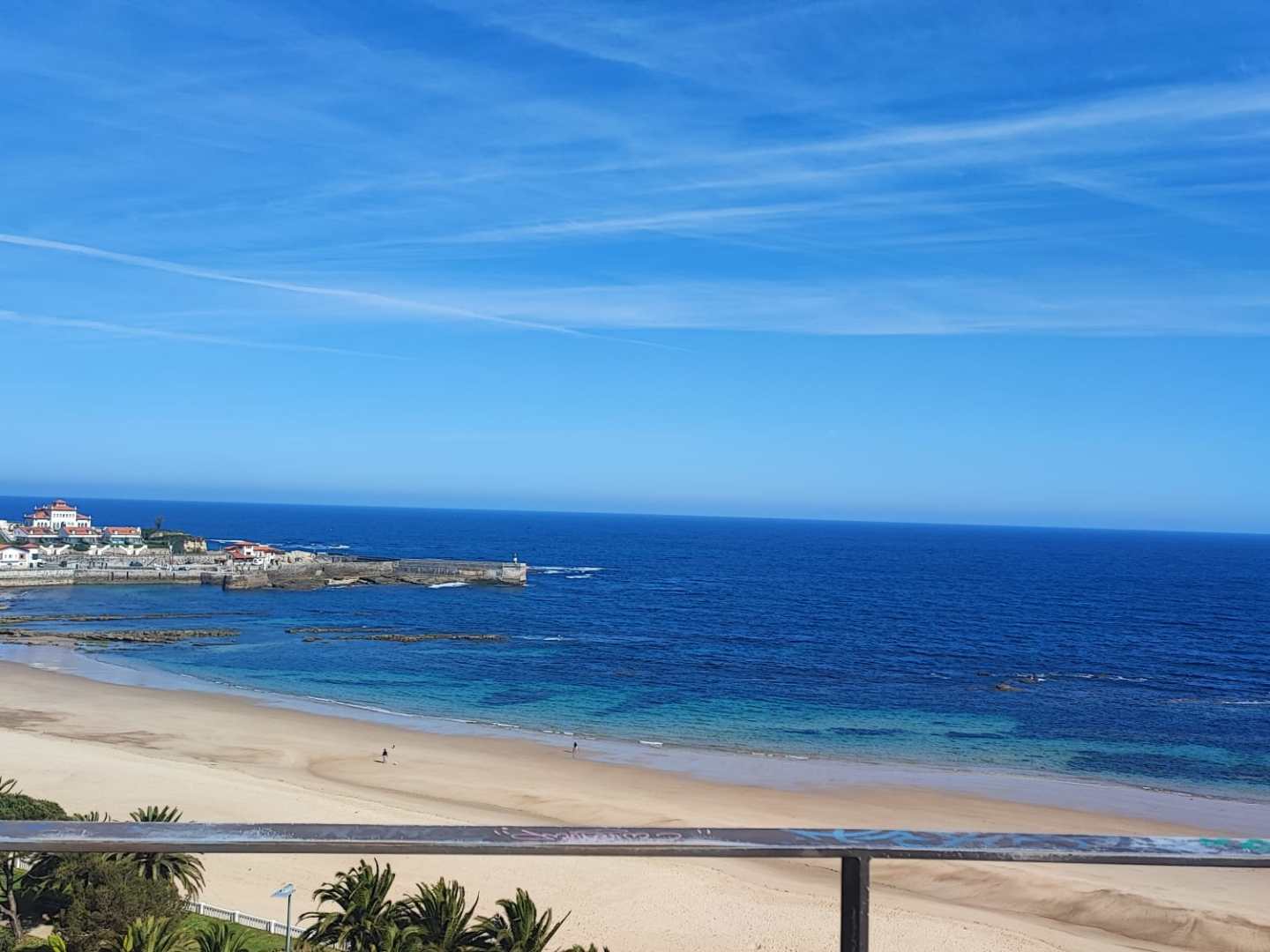 Beachfront view with sandy shore, blue ocean, and clear sky.