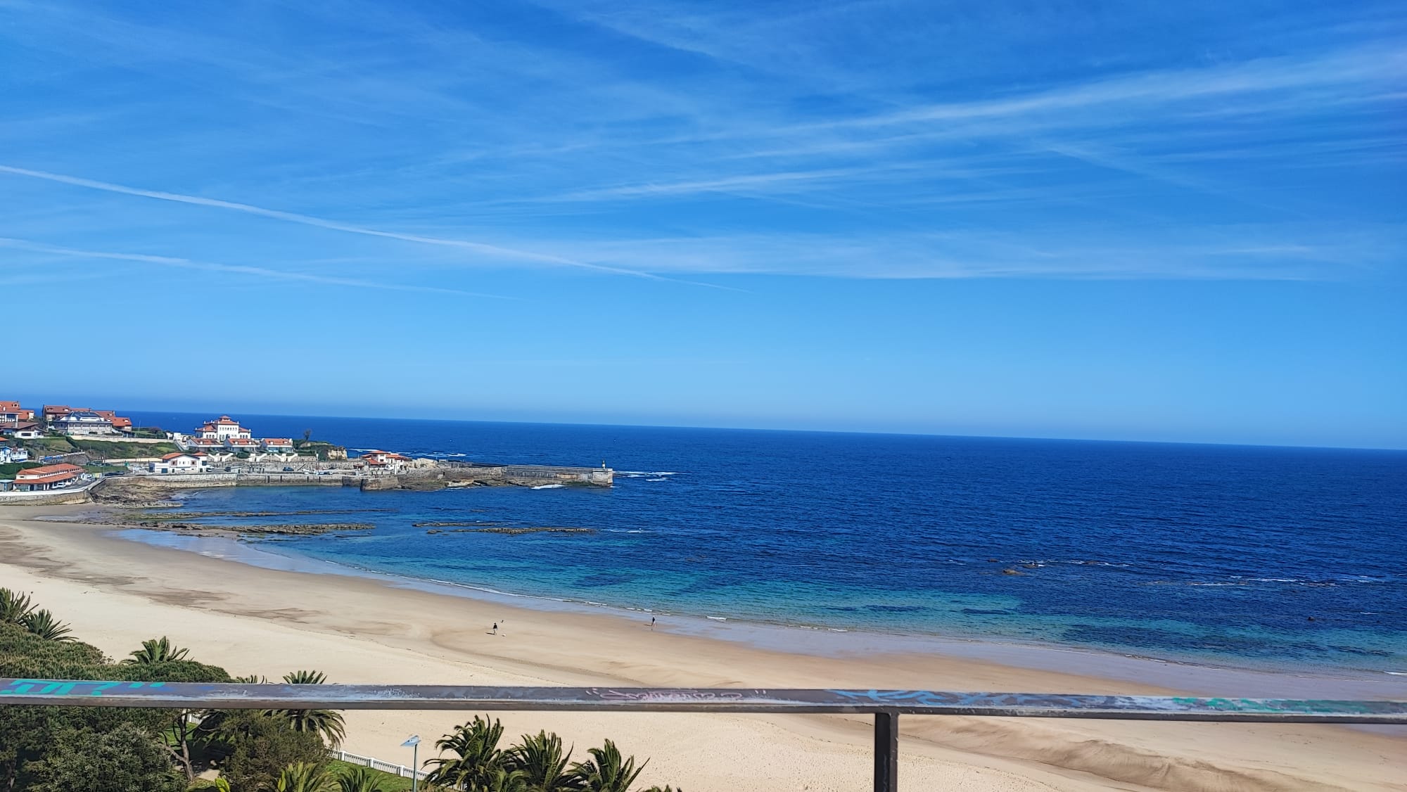 Beachfront view with sandy shore, blue ocean, and clear sky.