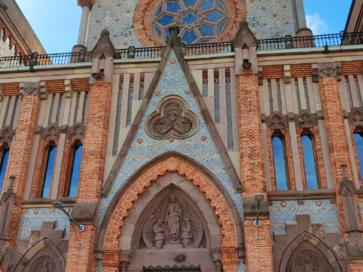 Front view of a brick Gothic-style church facade against a blue sky.